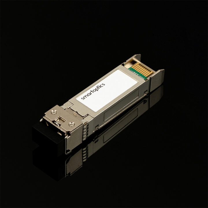 A metal SFP module labelled "smartoptics" lies on a glossy black surface.
